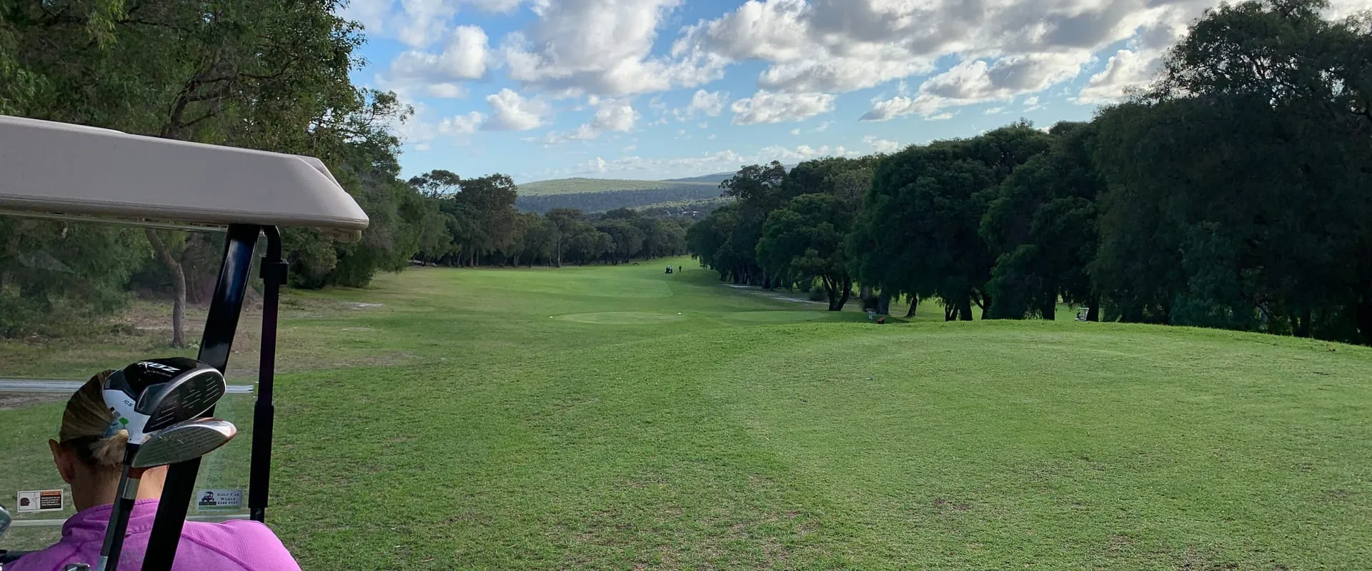 A tree-lined fairway in Margaret River seen from the seat of a golf cart