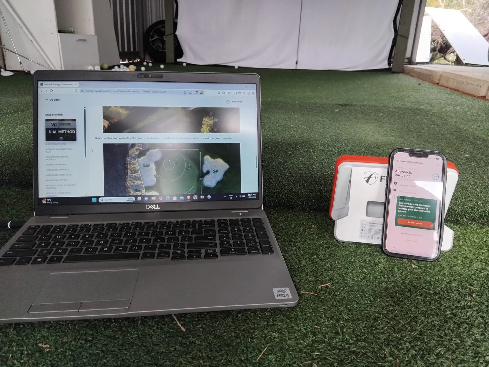 A laptop showing a DIAL Method lesson beside a phone running the DIAL Practice app, both set up on the turf of a practice bay
