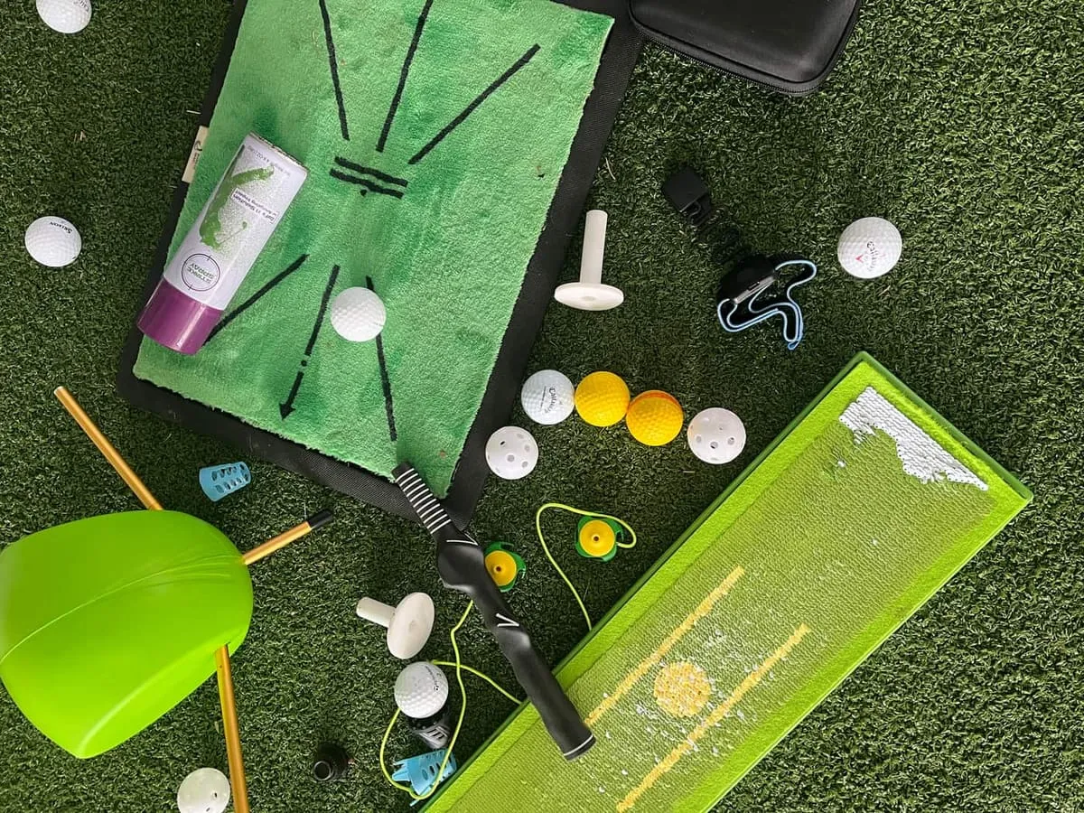 Training aids, alignment sticks, practice balls, a strike mat and an impact board spread across the turf