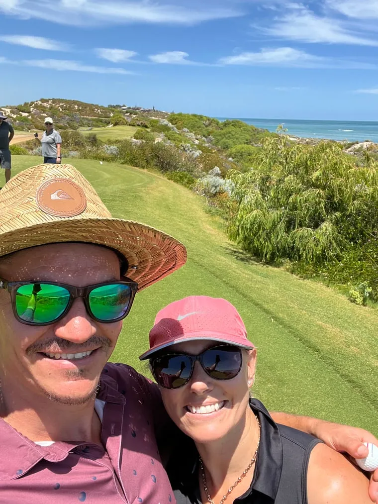 Todd and his playing partner in sunglasses on a coastal green, ocean behind them