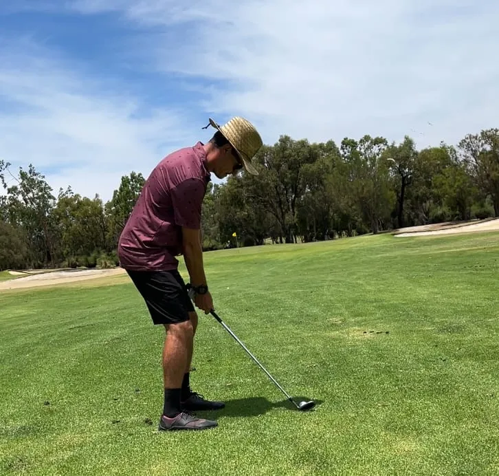 Todd lining up an approach shot from the fairway on a sunny day