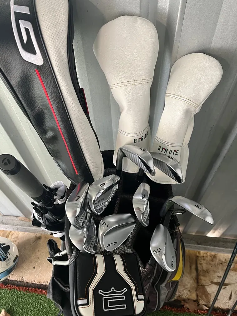 A bag of newly fitted irons, wedges and headcovered woods standing against a wall
