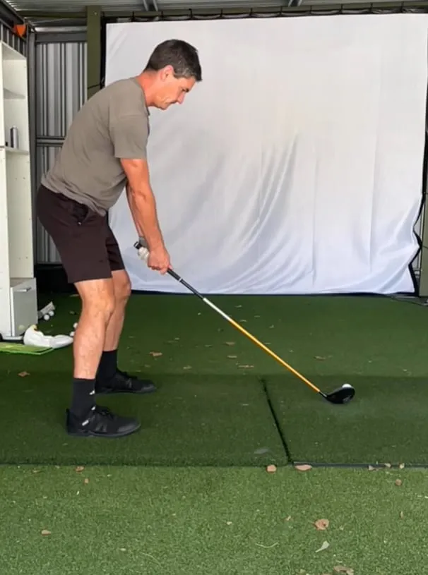 Todd at address on the mat in his home practice bay, hitting into a net and screen