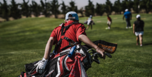 a man in a red shirt and blue hat with a golf bag